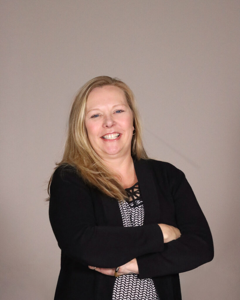 Christine Banks, the office manager of Awnings by Bigley & Hogshire stands proudly with her arms crossed, wearing a smile.