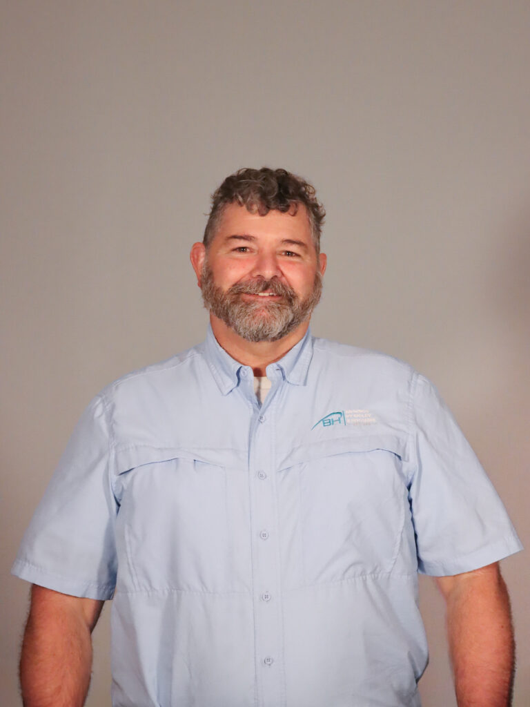 Taylor Bigley, the President of Awnings by Bigley & Hogshire stands proud to serve the company with a smile. He is wearing a button up short sleeve shirt with the company logo.